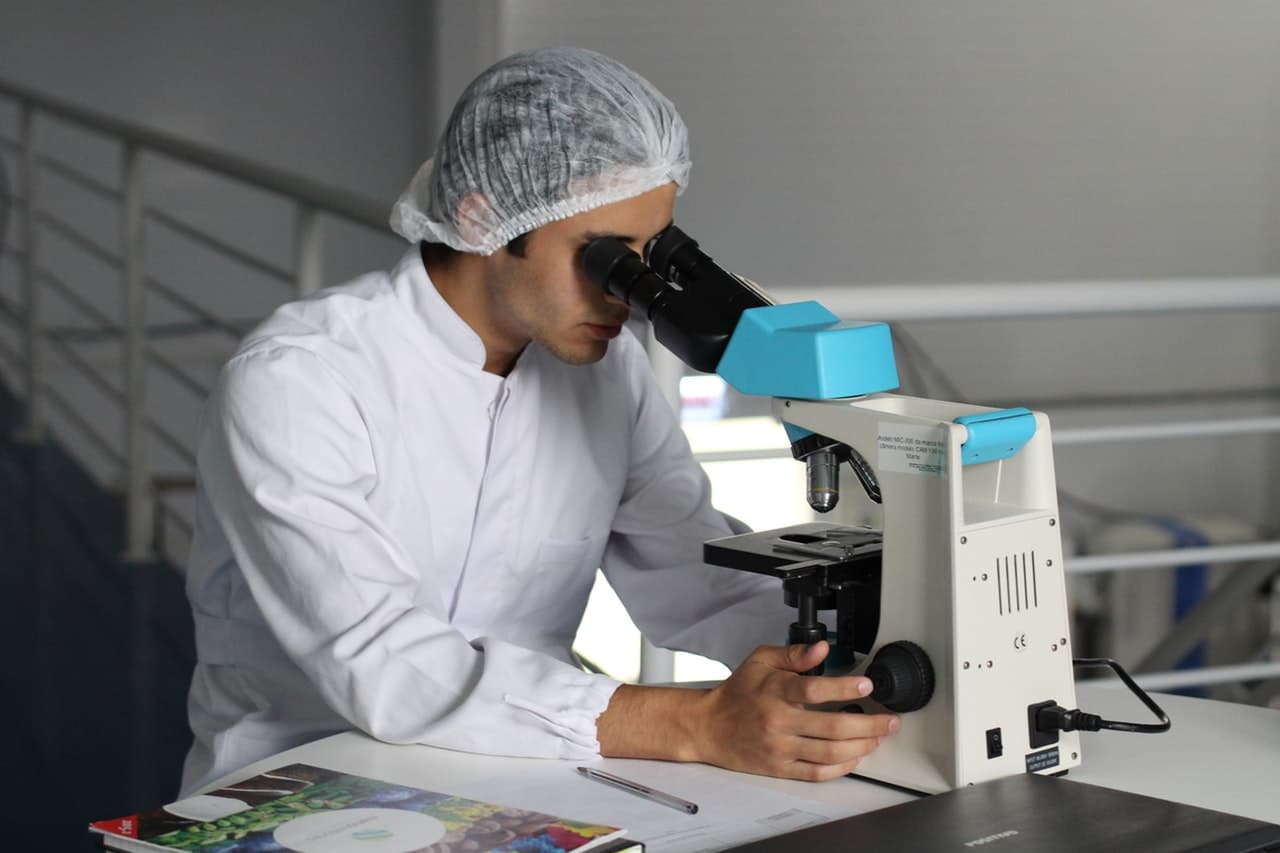 Olympia Pharmacy employee looking into microscope to study TriMix injection medication