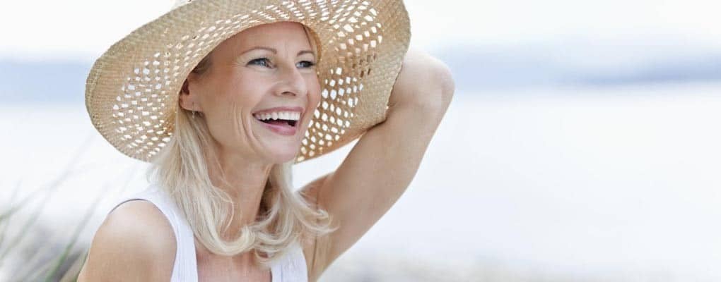 Middle-aged woman with sun hat smiling and looking out