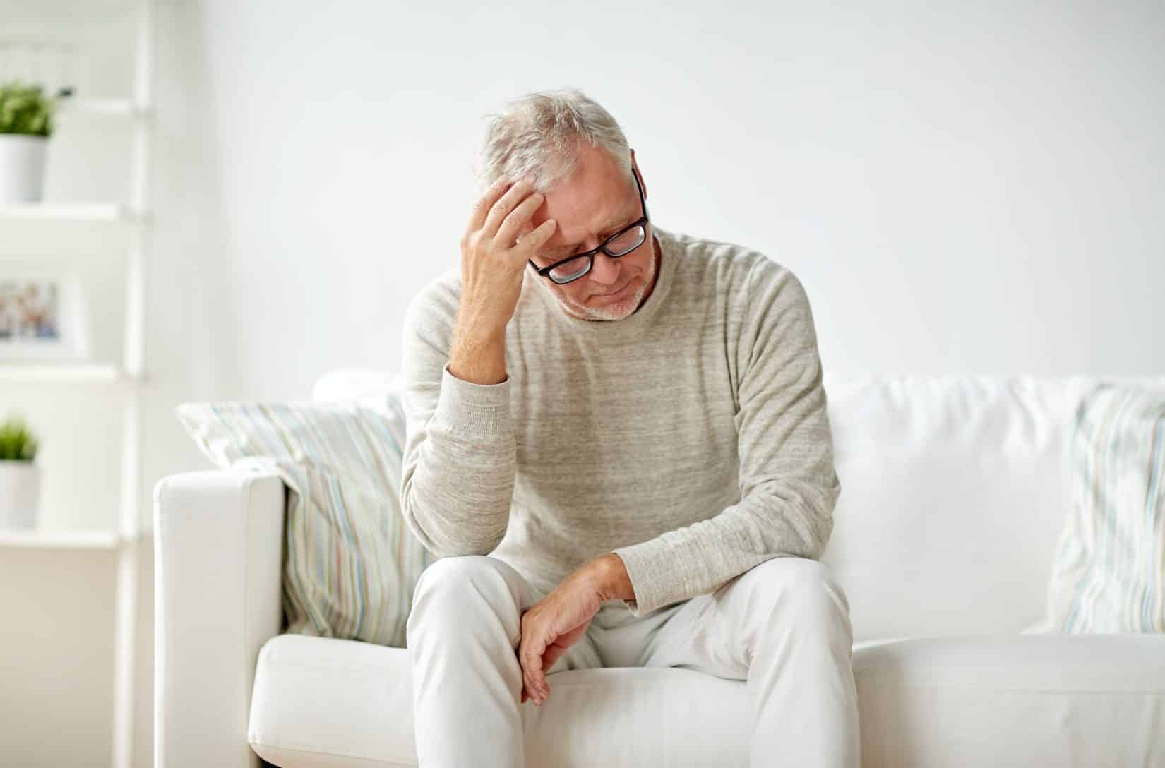 Worried Senior Man Sitting on Couch Thinking About TriMix for Erectile Dysfunction
