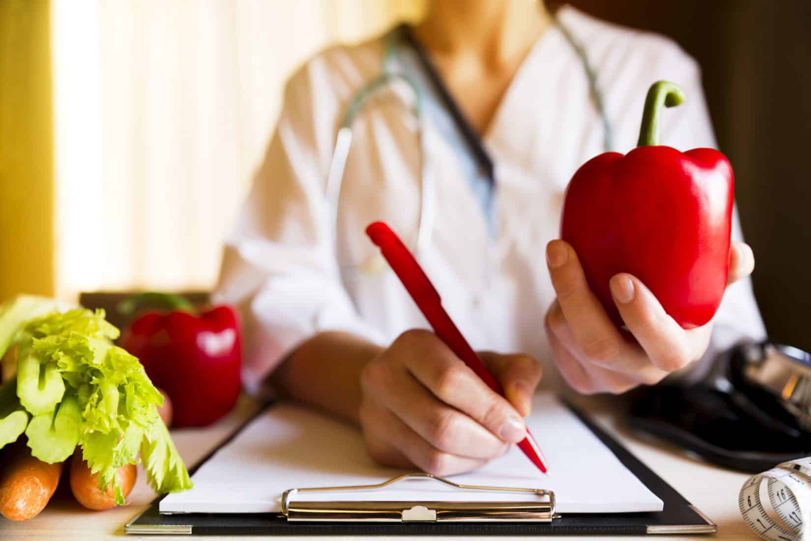 Woman holding up apple whlie writing something with a pen - Medical Weight Loss Program and Prescription Weight Loss Injections
