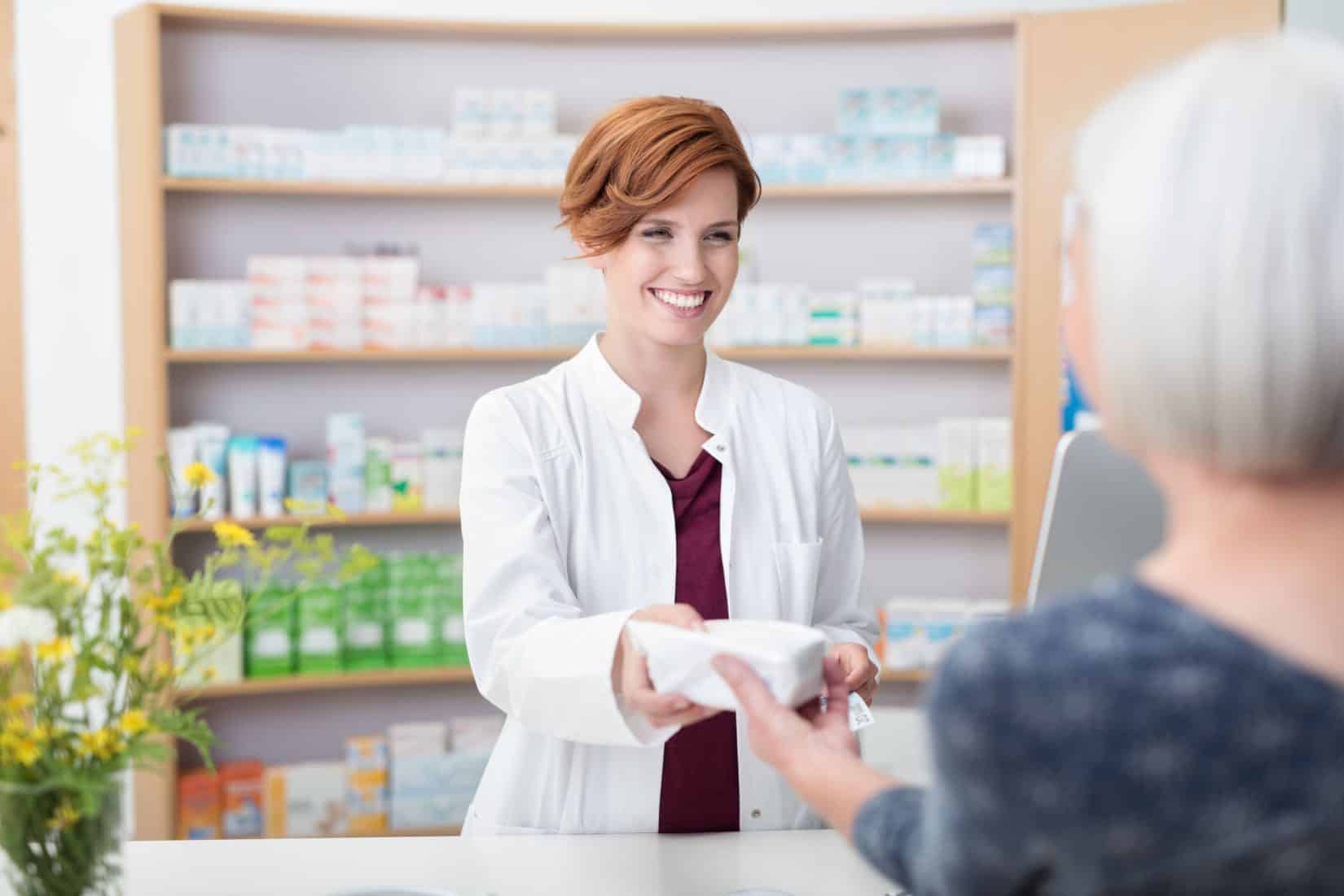 Red-headed woman giving prescription to older white-haired woman