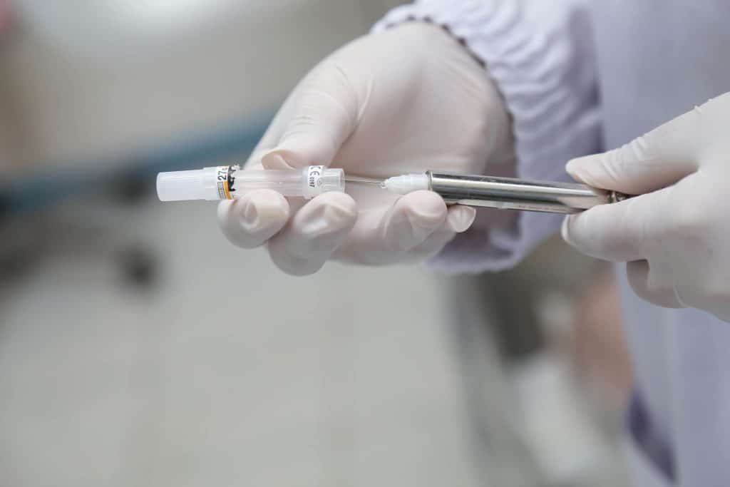 Gloved hands holding an injection needle