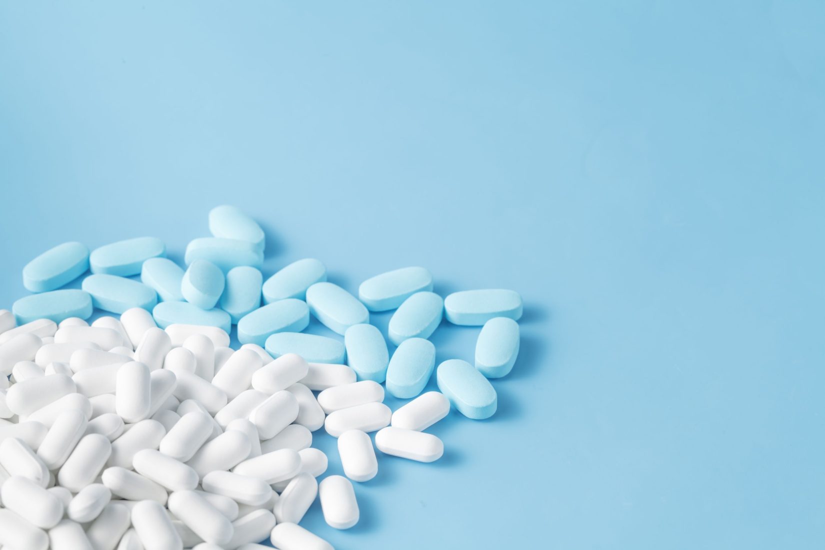 White and blue pills on a blue background