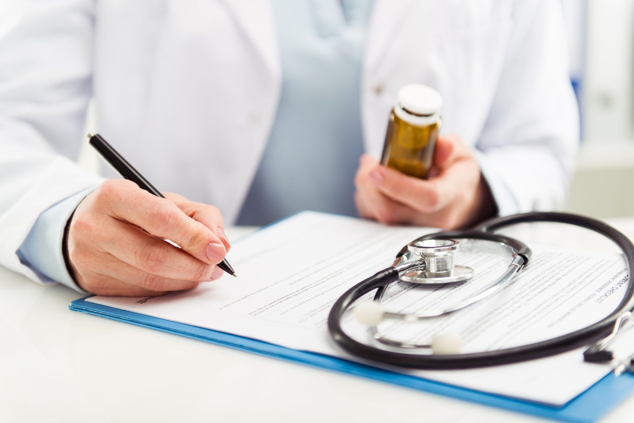 Doctor writing down information while looking at pill bottle