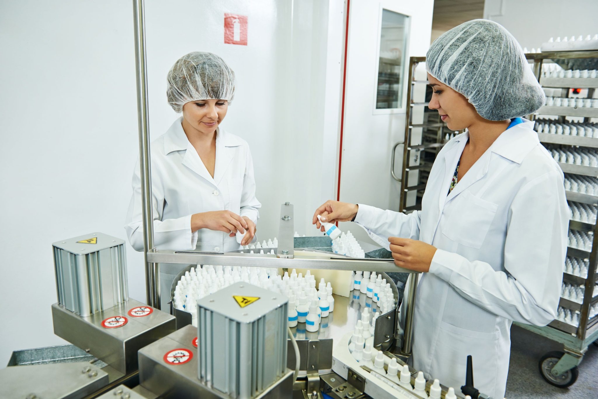 Pharmacists checking prescription bottles being produced in a compounding facility
