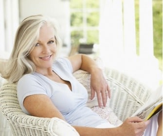 White older woman lounging in wicker chair and reading a book