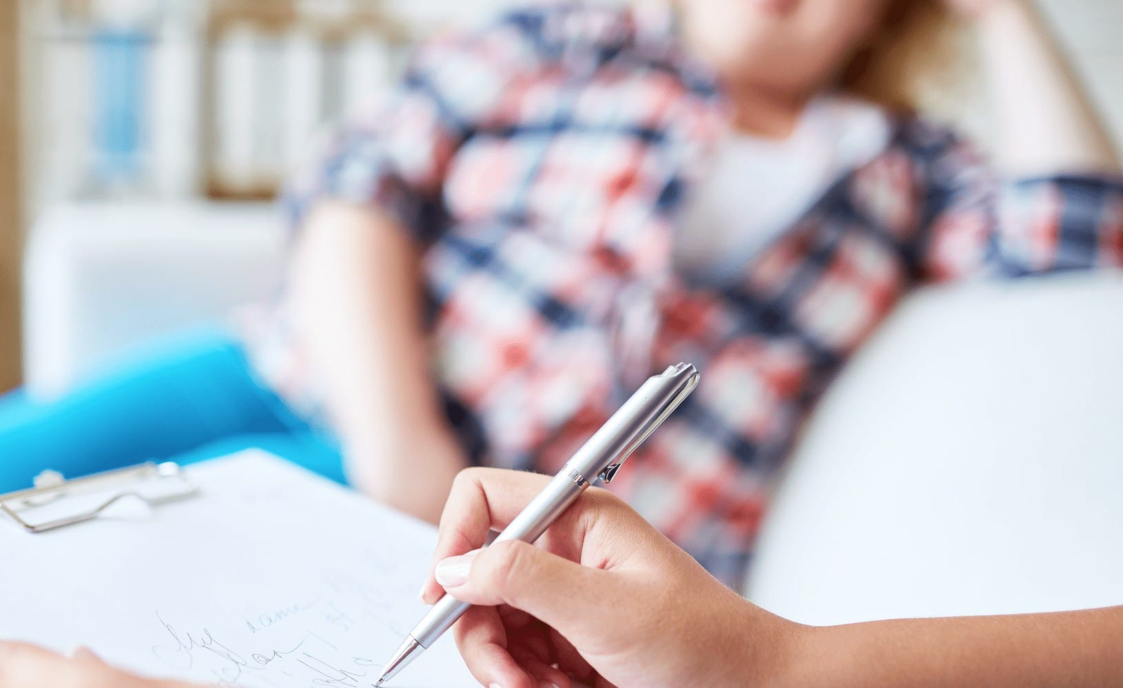 Doctor taking notes while in session with overweight patient.