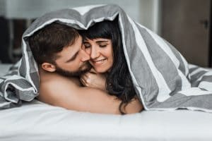 Man and woman hugging in bed.