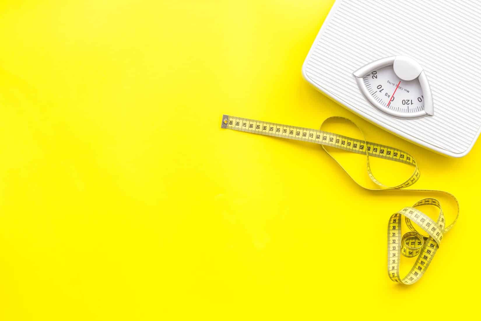 Scale and measuring tape on bright yellow background.