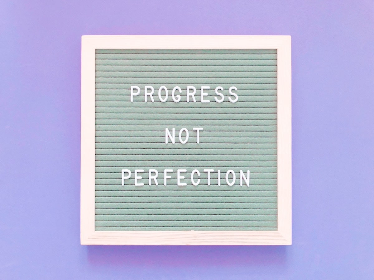 "Progress not perfection" on a purple background.