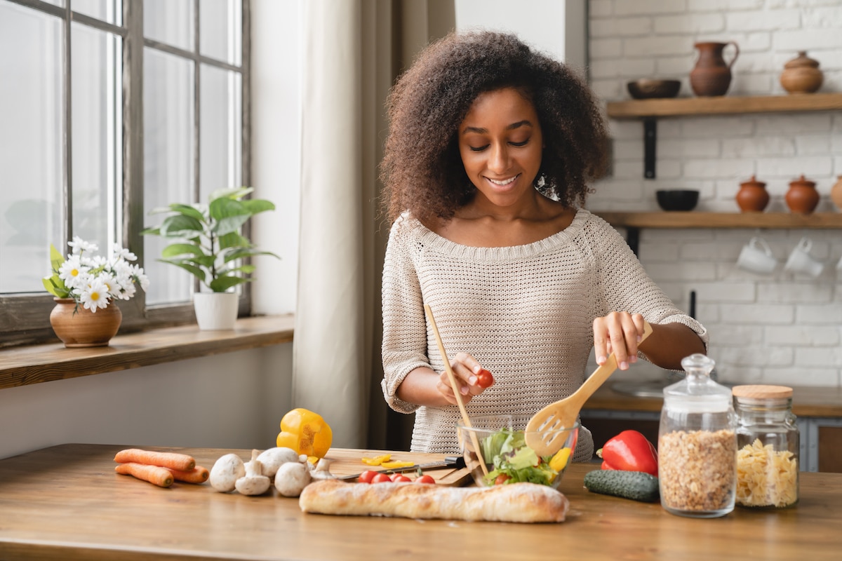 A woman prepping her meal in the kitchen to learn how to stay motivated for weight loss.
