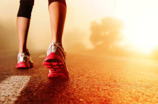 Shot of a persons wearing running shoes on a road.