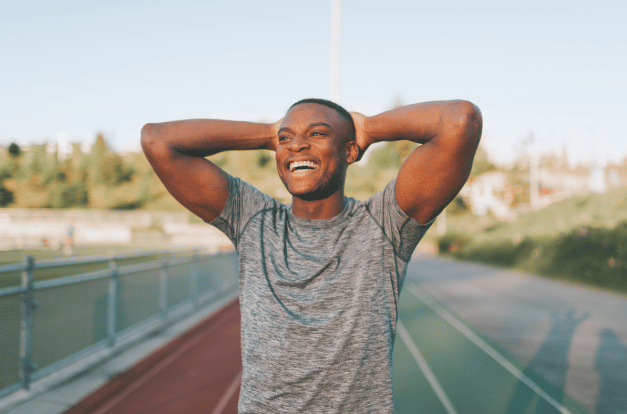 Man smiling looking into the distance on a sports track.
