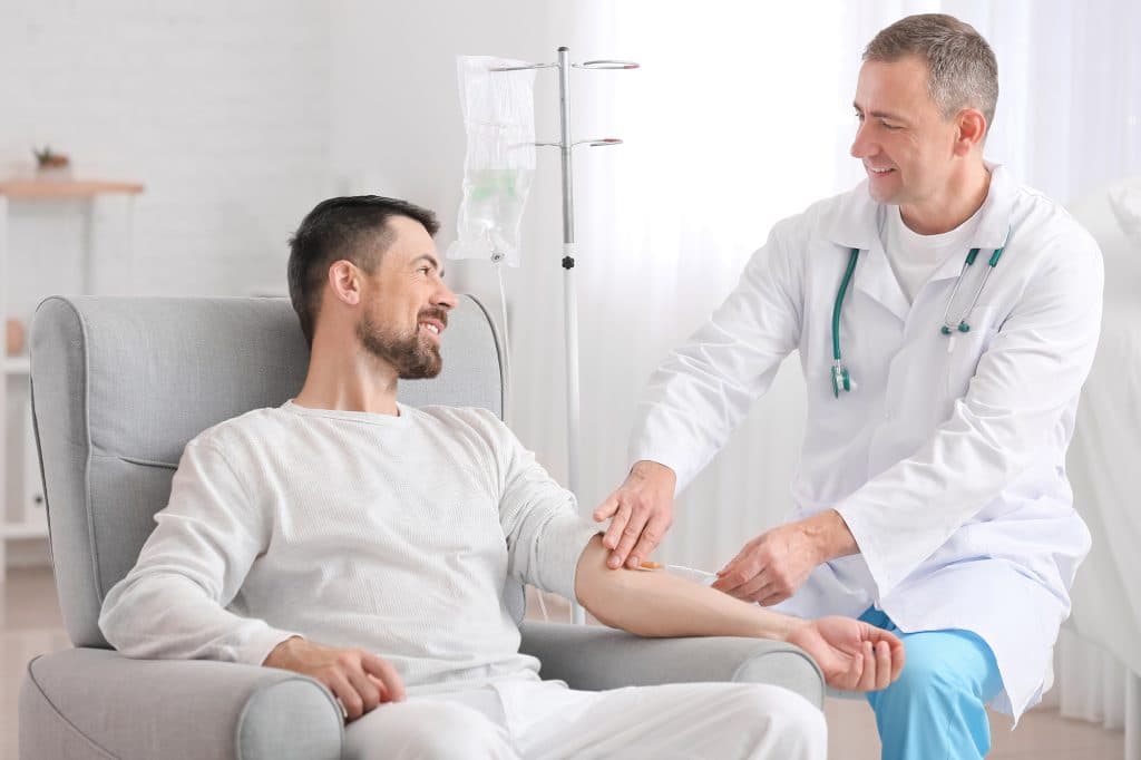 Doctor and man sitting undergoing course of treatment through an IV.