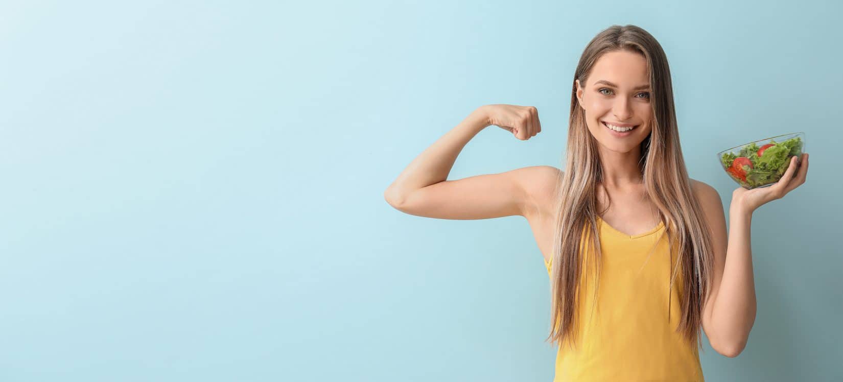 Woman holding a salad and flexing