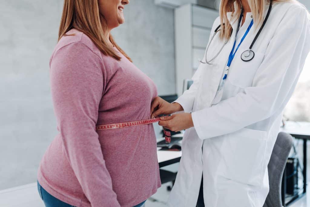 Nutritionist measuring waist of overweight woman in weight loss clinic