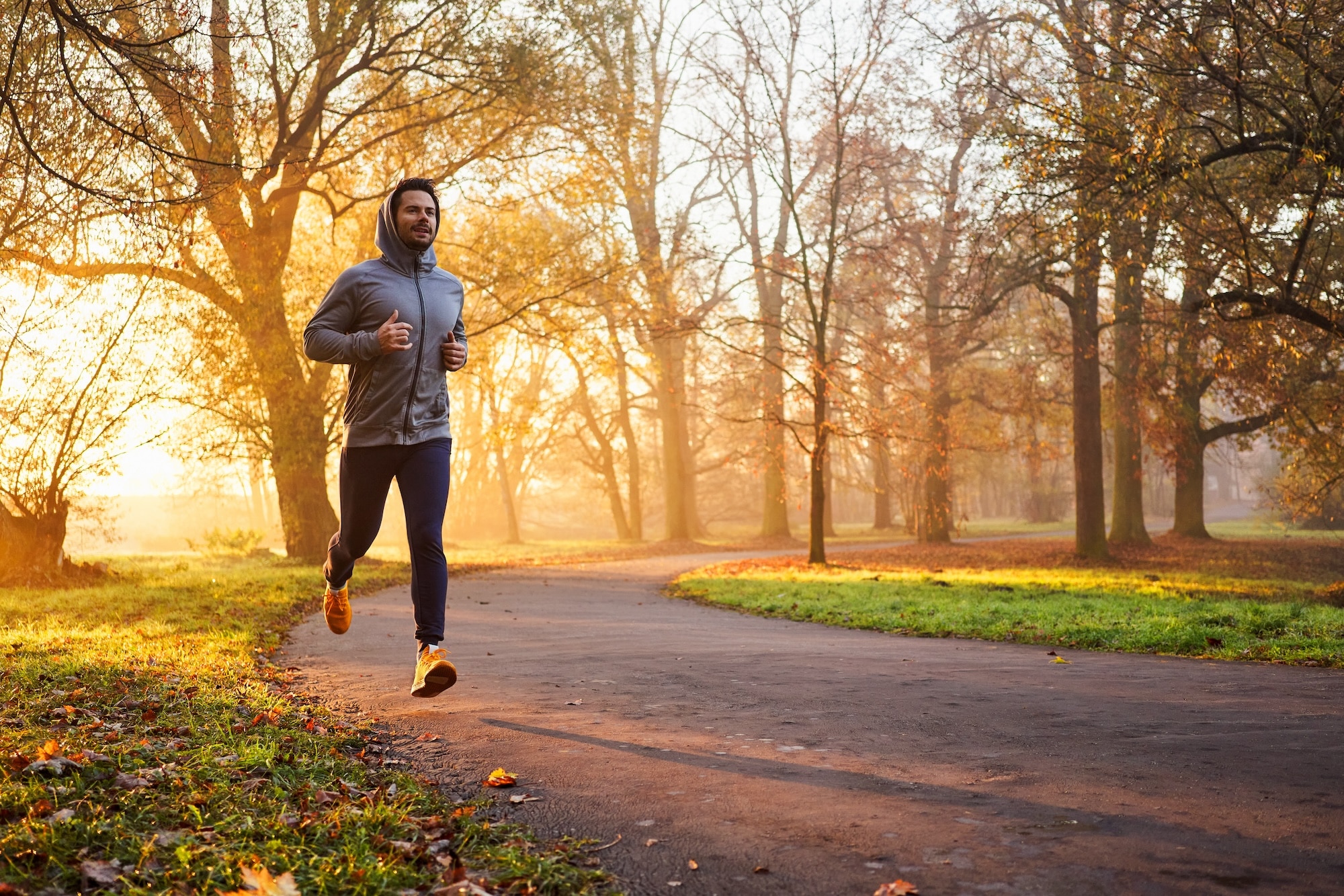 Man in a hoodie jogging on a trail