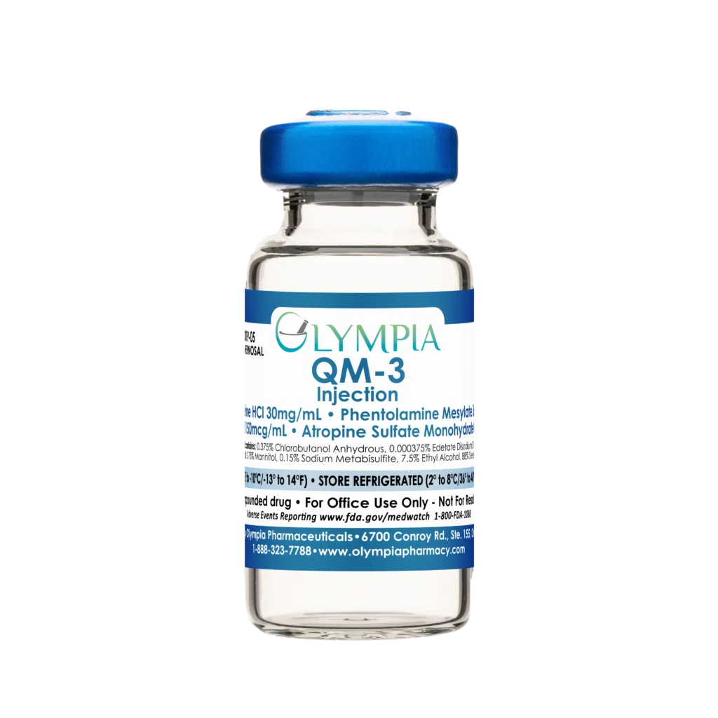 A vial of compounded Quadmix ED medication from Olympia. The vial has a blue cap and a blue label that reads "Olympia QM-3 Injection."