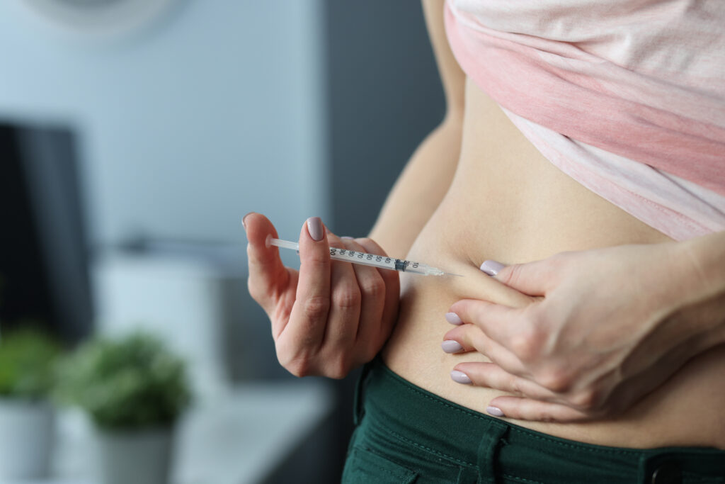 A woman administering a subcutaneous injection into her abdomen using a syringe.