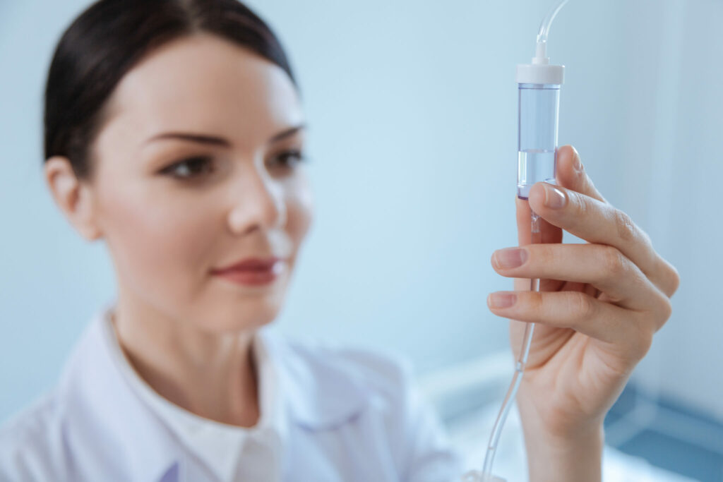 Female healthcare professional inspecting an IV drip, preparing for intravenous administration.