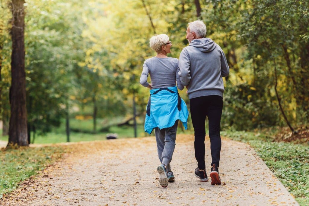 A view of a mature couple walking surrounded by trees.