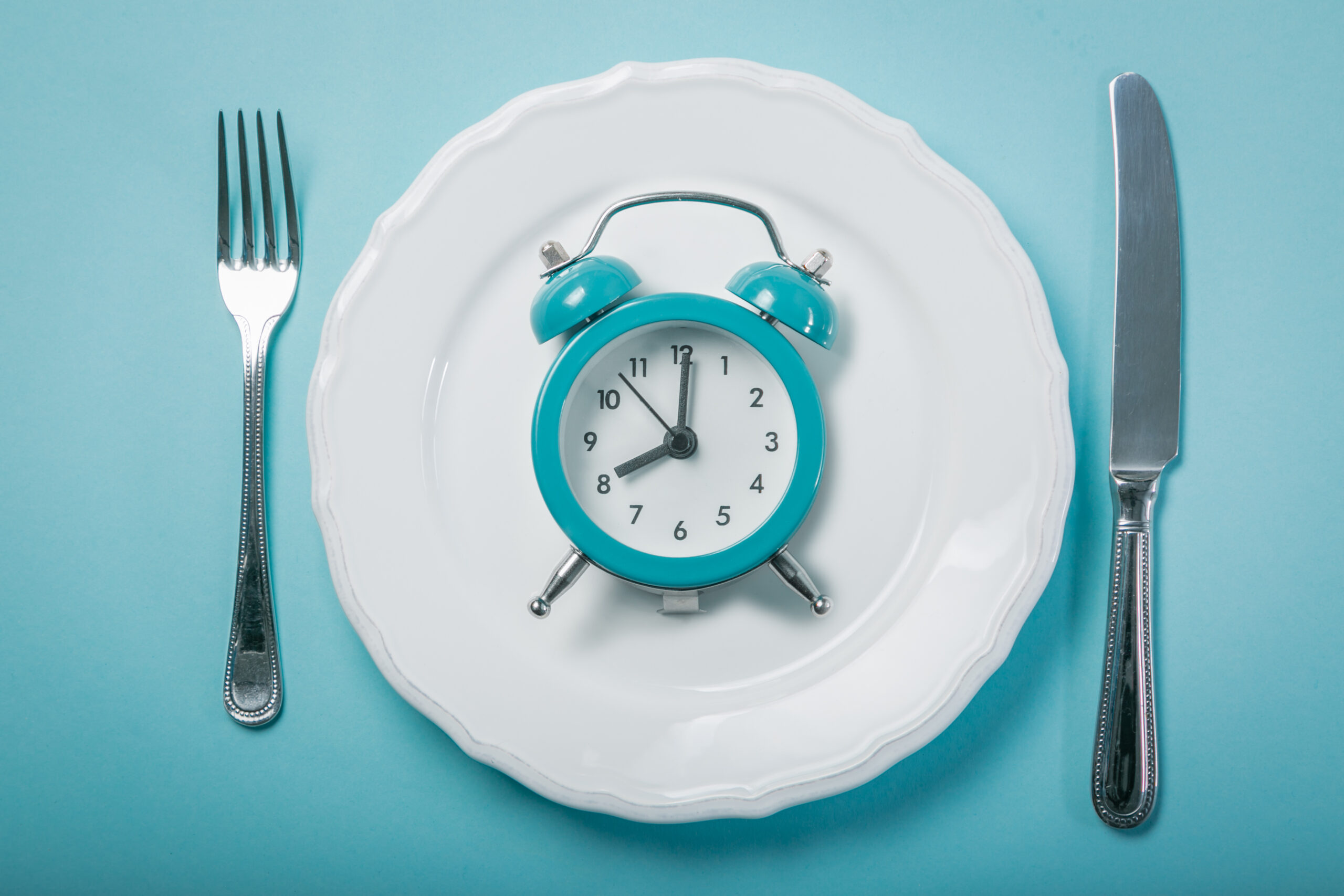 Intermittent fasting concept - empty plate on blue background, copy space